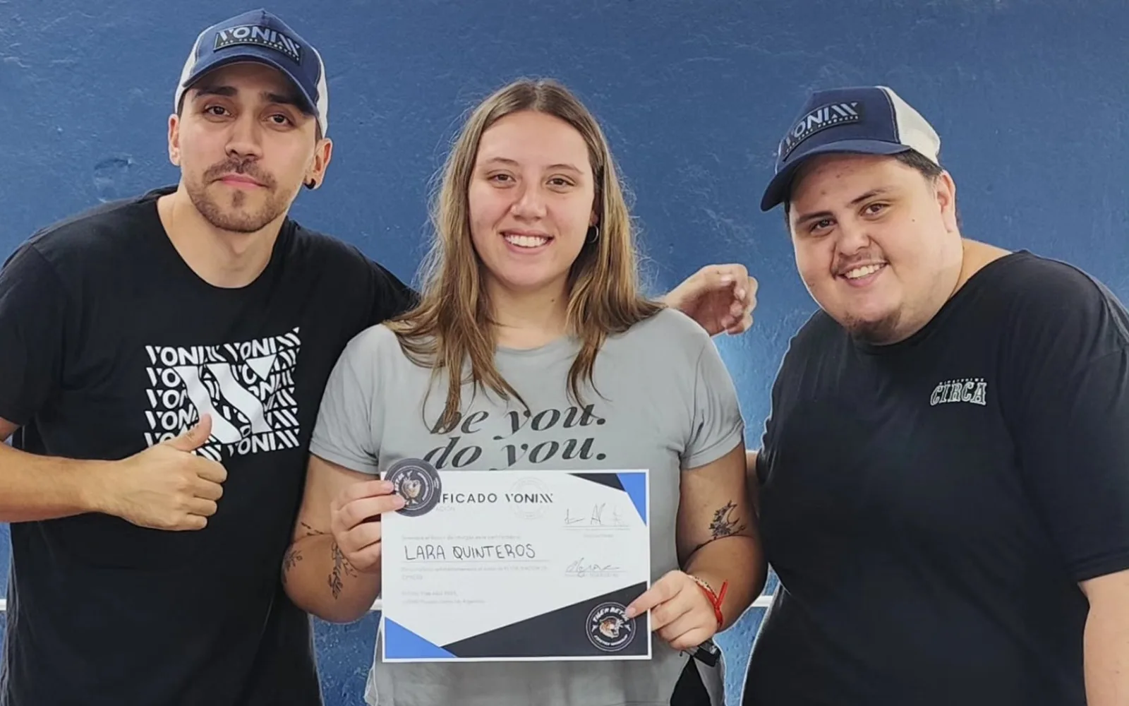 Los instructores junto a una alumna con su certificado